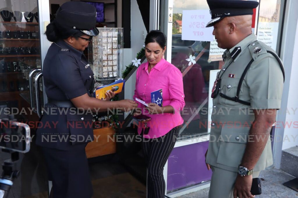 ACP Wayne Mystar watches as a policewoman gives a woman a pamphlet during a confidence patrol in San Fernando on November 22. Recent initiatives including greater police visibility have borne fruit with a reduction in murders over the past three months. - Photo by Ayanna Kinsale