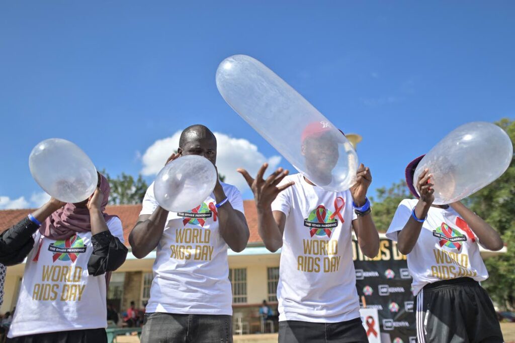 Peer educators compete to inflate condoms during a condom olympics presided over by self declared Africa King of Condoms, Stanley Ngara, a Kenya national, during a World Aids Day commemoration at the Kenyatta University campus in Nairobi on December 1, 2021.  - AFP PHOTO