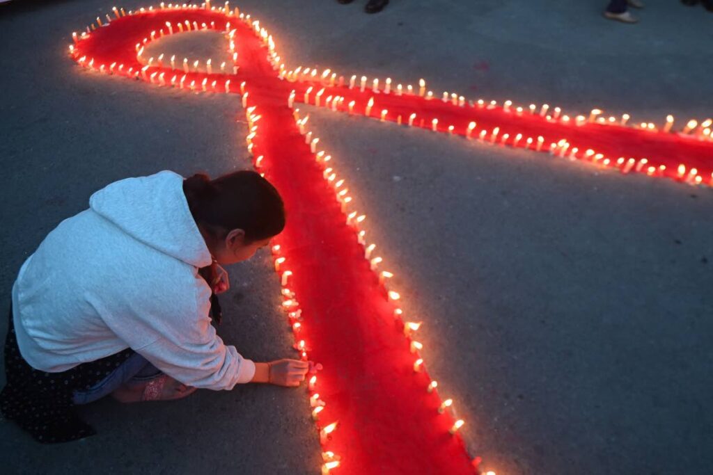 A girl light candles arranged in a red ribbon shape during a World Aids day event in Kathmandu, Nepal on November 30. - AFP PHOTO