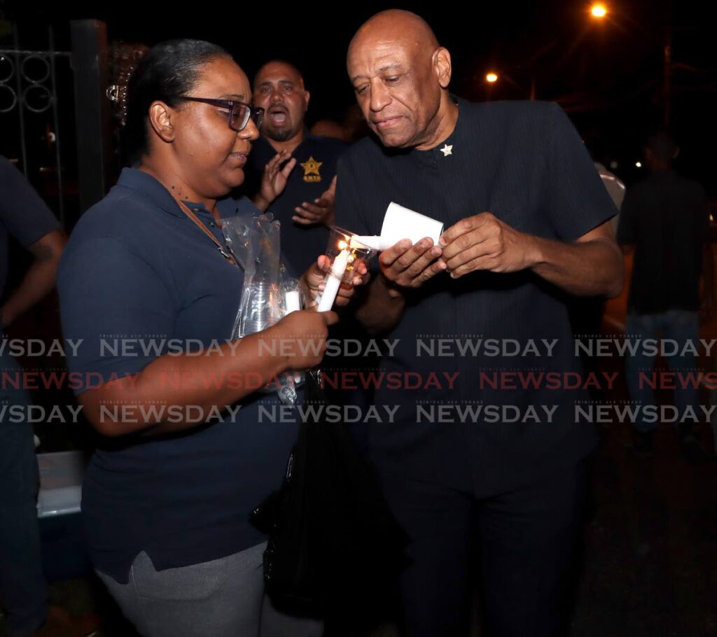 President General of the Oilfield Workers Trade Union  Ancel Roget on right, gets his candle lit at a protest by T&TEC employess and OWTU members, in front of the Prime Minister's residence, St Ann's on November 29. FILE PHOTO/ANGELO MARCELLE -