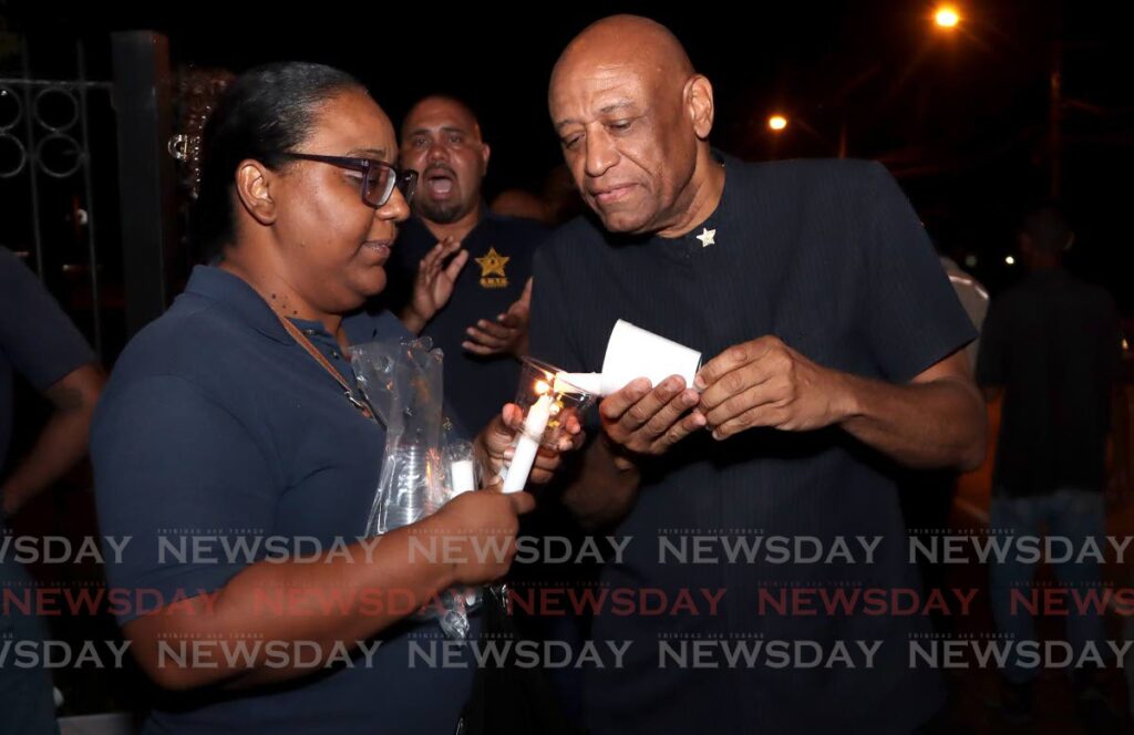 President General of the Oilfield Workers Trade Union  Ancel Roget on right, gets his candle lit at a protest by T&TEC employess and OWTU members, in front of the Prime Minister's residence, St Ann's on November 29. - File photo by Angelo Marcelle