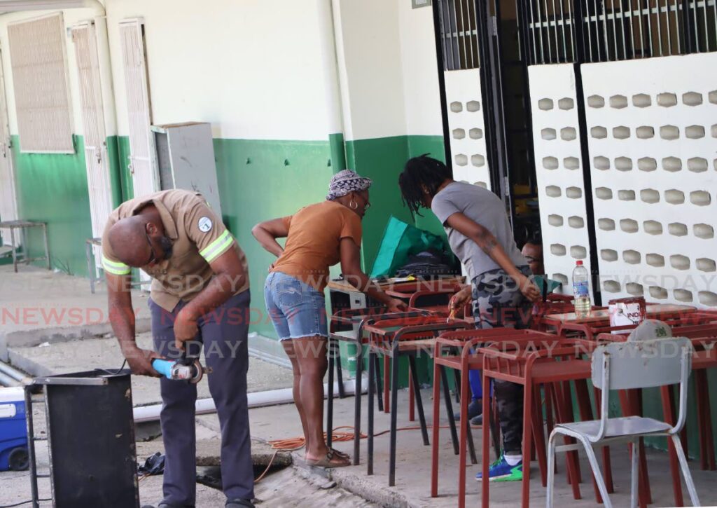 St George's College Parent-Teacher-Student Association members refurbish school desks on November 30 in Barataria. - Ayanna Kinsale