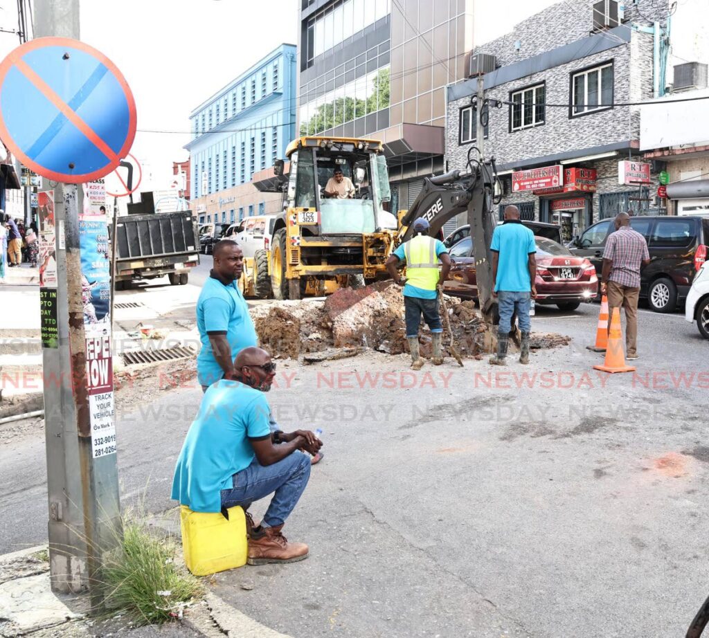 WASA workers dig a trench in order to begin repairs on a leaking line on High street San Fernando on December 3. - Photo by Lincoln Holder