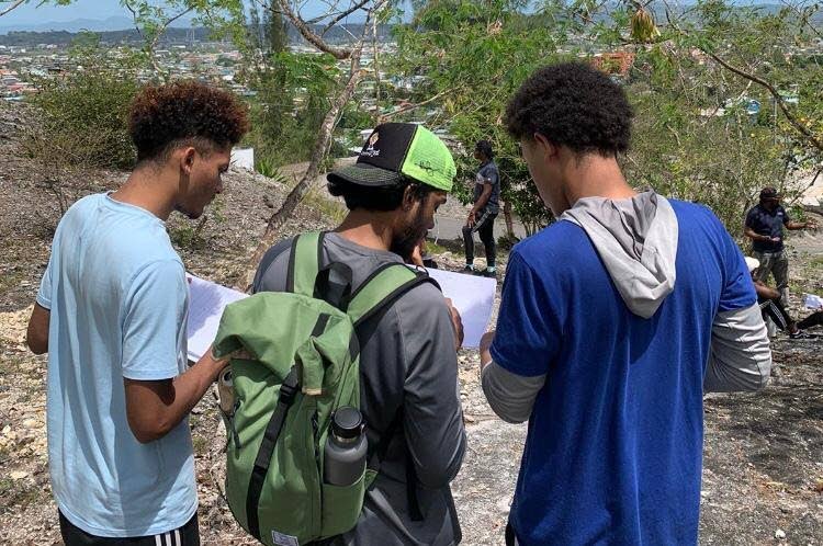 Petroleum geoscience students Darian Lewis, left, Saleem Khan and Elijah Roberts discuss their field sketches at the Naparima Hill Outcrop. - Photo courtesy GSTT