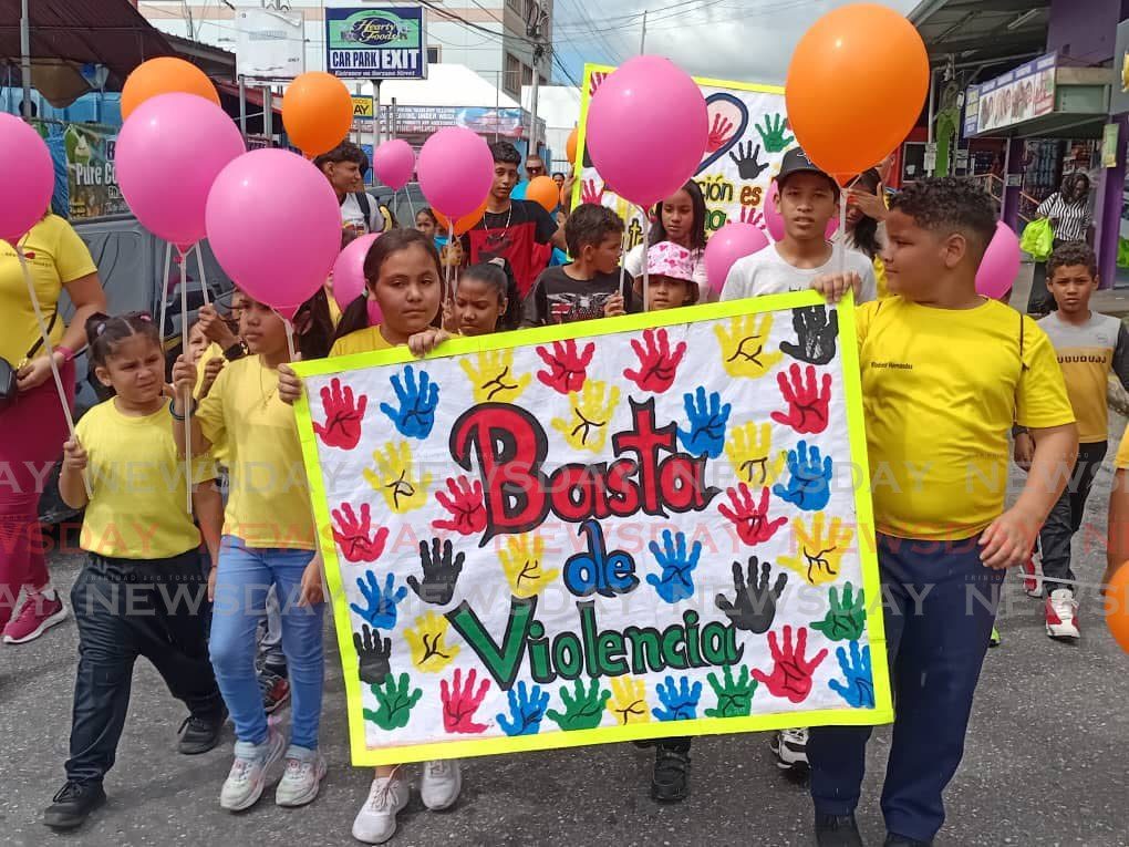 Migrant children, who are members of the La Casita Hispanic Cultural Centre, participate in the march in Arima on December 1. The banner reads