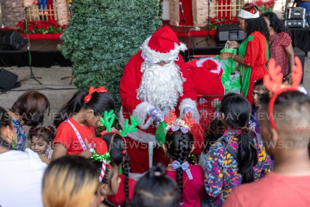 GATHER 'ROUND CHILDREN! Santa Claus spreads holiday cheer as he greets and hands out gifts to children at C3 Centre, San Fernando, on December 8. - Photo by Jeff K Mayers