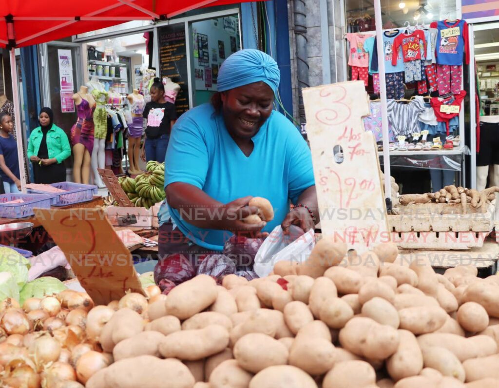 Sharon Daniels places potatoes in a bag for a customer at her vegetable stall on Charlotte Street, Port of Spain. FILE PHOTO - Ayanna Kinsale