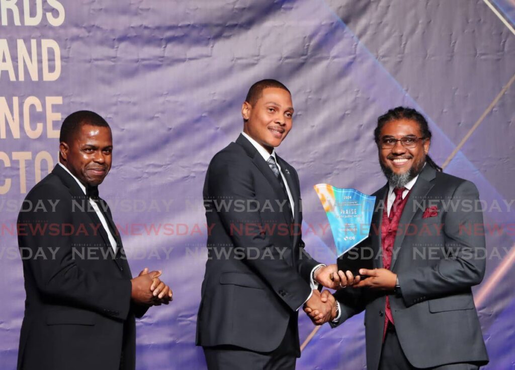 Acting President Nigel de Freitas, centre, presents the PrAISE award for public sector innovation to COSTAATT's vice president IT and Digital Transformation Kevin Ramsoobhag at the Hyatt Regency, Port of Spain, on December 10. Looking on is IDB Country Representative Julian Belgrave. - Photo by Ayanna Kinsale