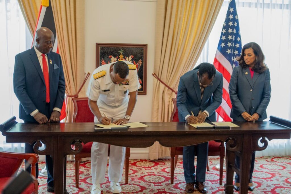 Commander of US Southern Command Adm Alvin Holsey, second from left, and Minster of National Security Fitzgerald Hinds sign the Southcom Human Rights Initiative at the Diplomatic Centre, Port of Spain on December 10. Looking on are the Prime Minister, left, and US Ambassador Candace Bond. PHOTO COURTESY US EMBASSY -