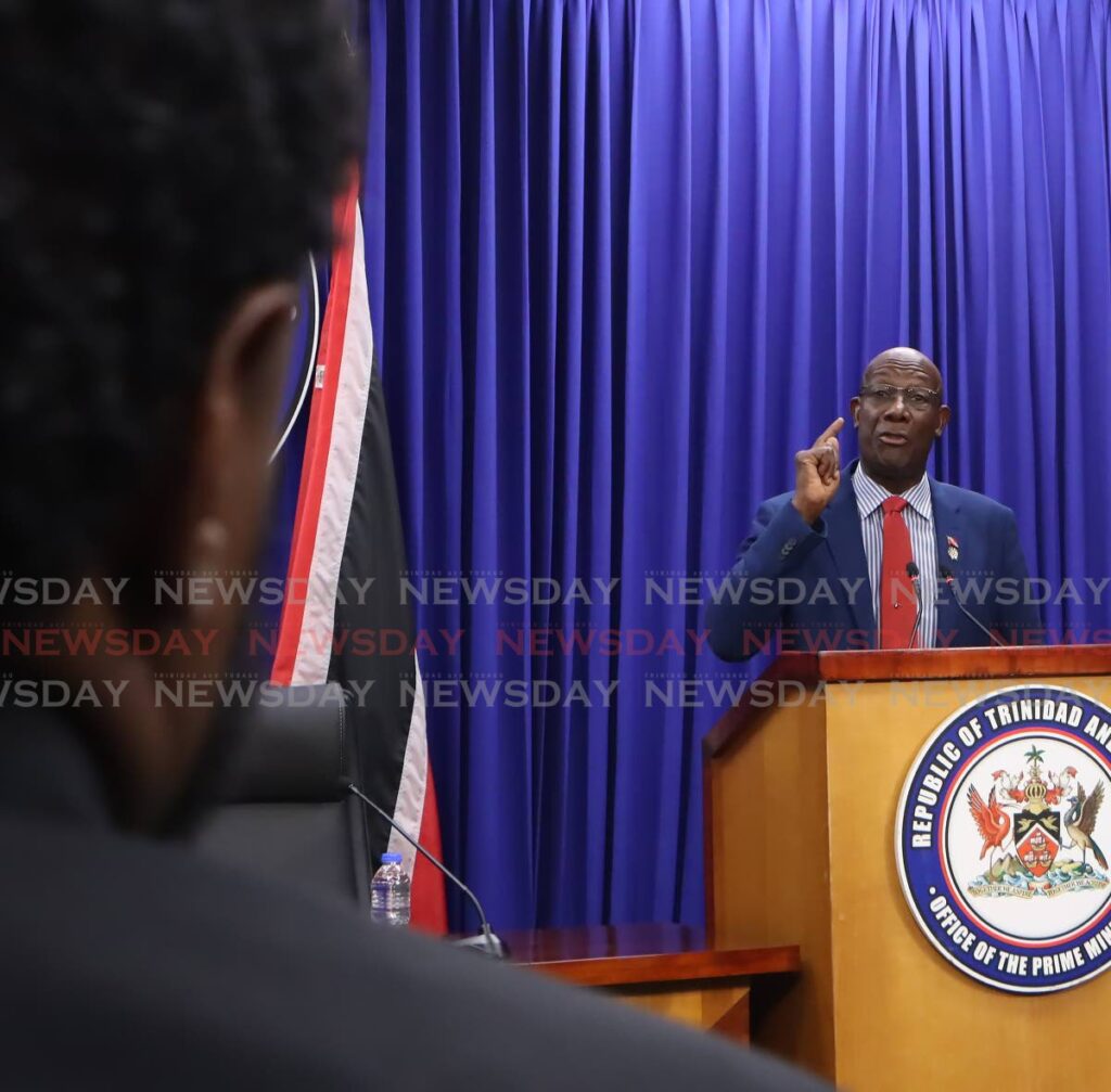 Newsday reporter Gregory McBurnie, left, listens as the Prime Minister responds to a Newsday article headlined “Government signs agreement as White House ups pressure on Maduro – US can put troops in TT,” at a post-cabinet media briefing at White Hall, Port of Spain on December 12. - Angelo Marcelle