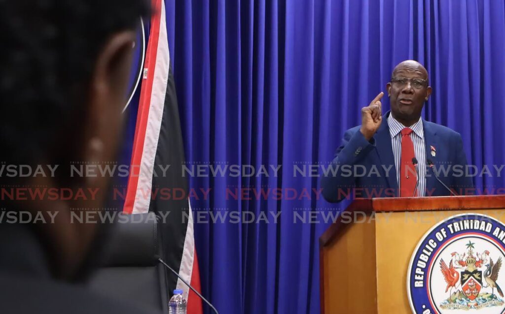 Newsday reporter Gregory McBurnie, left, listens as the Prime Minister responds to a Newsday article headlined Government signs agreement as White House ups pressure on Maduro – US can put troops in TT, at a post-cabinet media briefing at Whitehall, Port of Spain, on December 12. -Photo by Angelo Marcelle