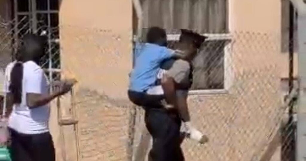 A screenshot of PC Wallace carrying an injured boy in Chaguanas. - 