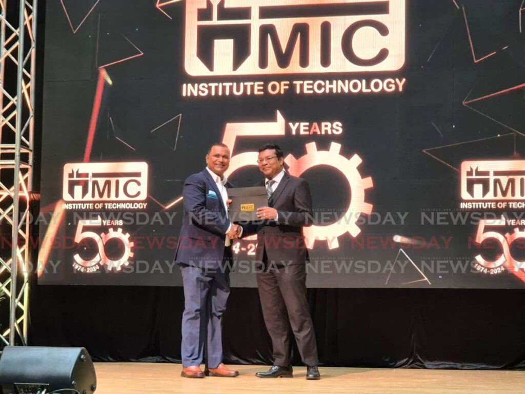 MIC-IT CEO Anil Ramnarine accepts a long service award for 17 years in service from director Winston Boodoo at MIC-IT's 50th Anniversary Celebration and Long Service Award Ceremony on December 10 at the Centre of Excellence, Macoya. - Paula Lindo