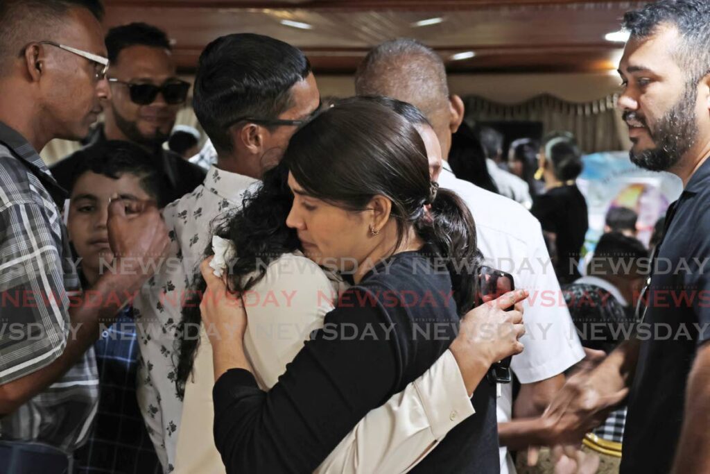 Mourners console each other at the funeral service of murder victim Sherry Ann Roett, held at David Guide and Son Chapel, Couva on December 13. - Photo by Lincoln Holder