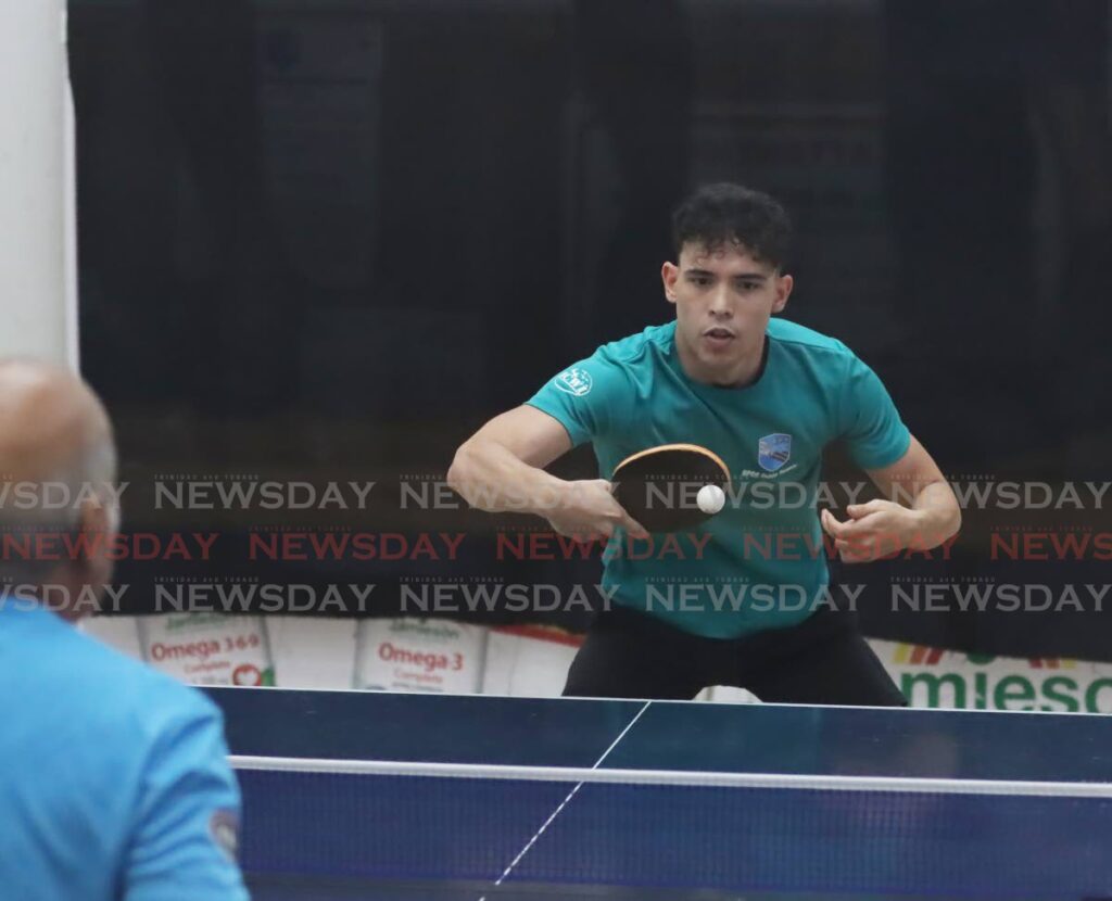 Daniel Henriques returns the ball to Wayne Dopson during the semifinals in division A of the QPCC Christmas Hamper Table Tennis tournament. - Ayanna Kinsale