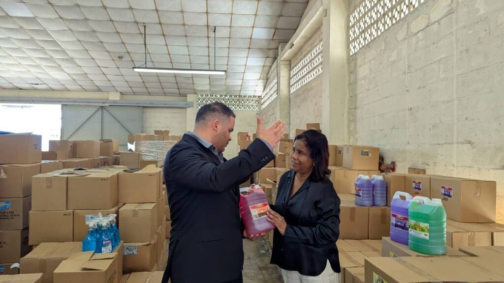 Jonathan Garcia, managing director of Christle Ltd, left, shows Paula Gopee-Scoon, Trade and Industry Minister, new labelling on the company's products at Christle Ltd's warehouse in O'Meara Industrial Estate on December 17.  - Mya Quamie