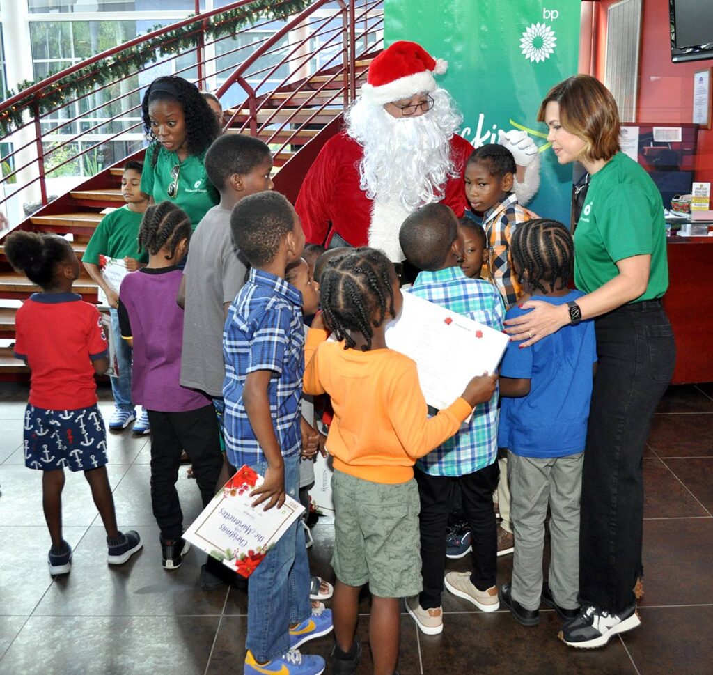 Giselle Thompson, vice-president, communications and external affairs, bpTT introduces  excited kids to Santa Claus. - 