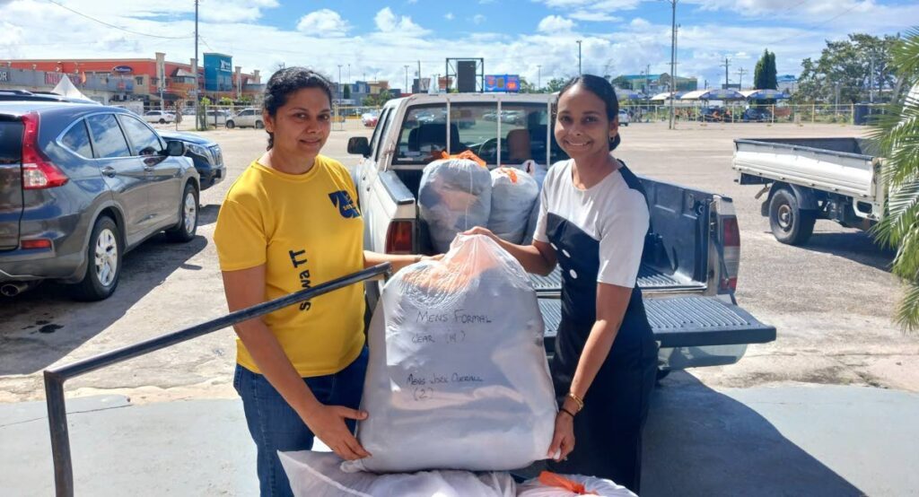 Varuna Samaroo, operations officer, Sewa International TT, hands over the items of clothing to  Jodi Dolabaille, communications officer, Ministry of Labour, for the second instalment of SuitUp for 2025. - 