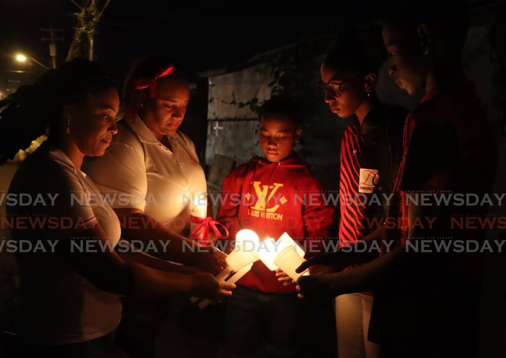 Attendees light candles before the vigil in memory of MP Lisa Morris-Julian and two of her children who perished in a December 16 fire. - Photo by Angelo Marcelle