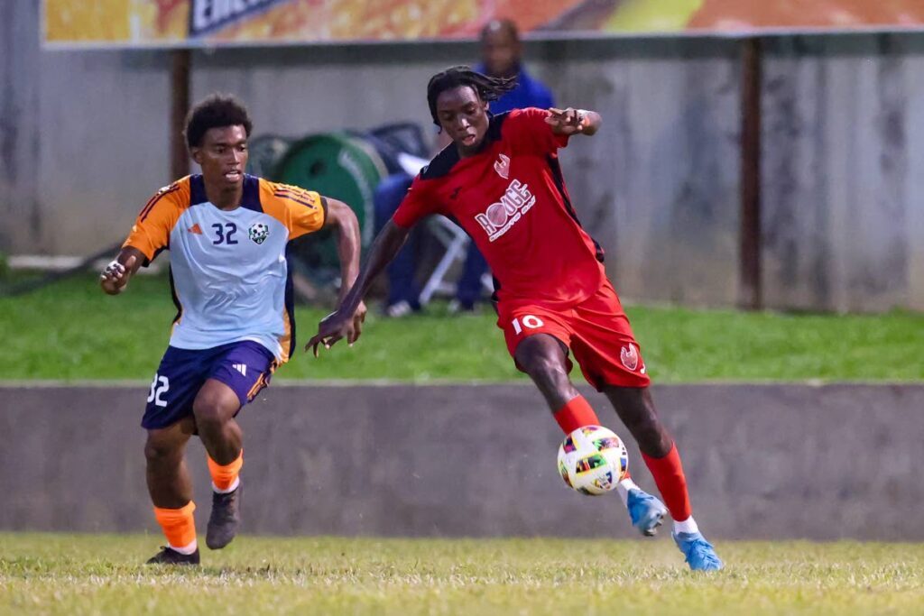 1976 FC Phoenix's Jariel Arthur (R) starts an attack ahead of Prison Service FC Josiah King during the TT Premier Football League match at the Police Barracks grounds on December 22, in St James. FC Phoenix won 2-1 - Photo by Daniel Prentice