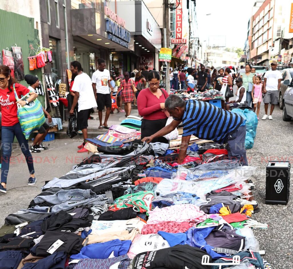 A vendor tends to a customer as he sells clothes on High Street, San Fernando, on December 23. - File photo by Lincoln Holder