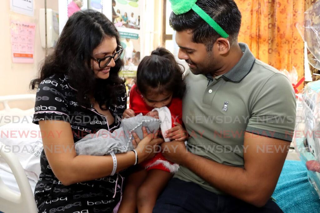 WELCOME TO THE FAMILY: Elizabeth Hamid kisses her brother Lucas Hamid after he was the first baby to be born on Christmas Day as their parents Amrita Gobin and Darren Hamid look on.  - Photo by Ayanna Kinsale