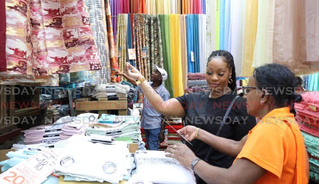 Lima McIntosh gets help with curtain options from a Mode Alive employee at Frederick Street, Port of Spain, on Boxing Day. - Photo by Faith Ayoung