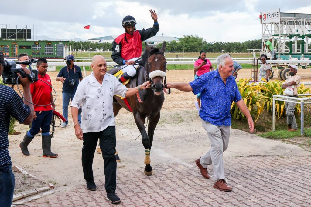 Hello World, with Dillon Khelawan aboard, is escorted to the winners' circle by owner Neil Poon Tip, left, and trainer John O'Brien after winning the First Citizens Gold Cup at Santa Rosa Park, Arima, on Boxing Day. - Photo by Daniel Prentice