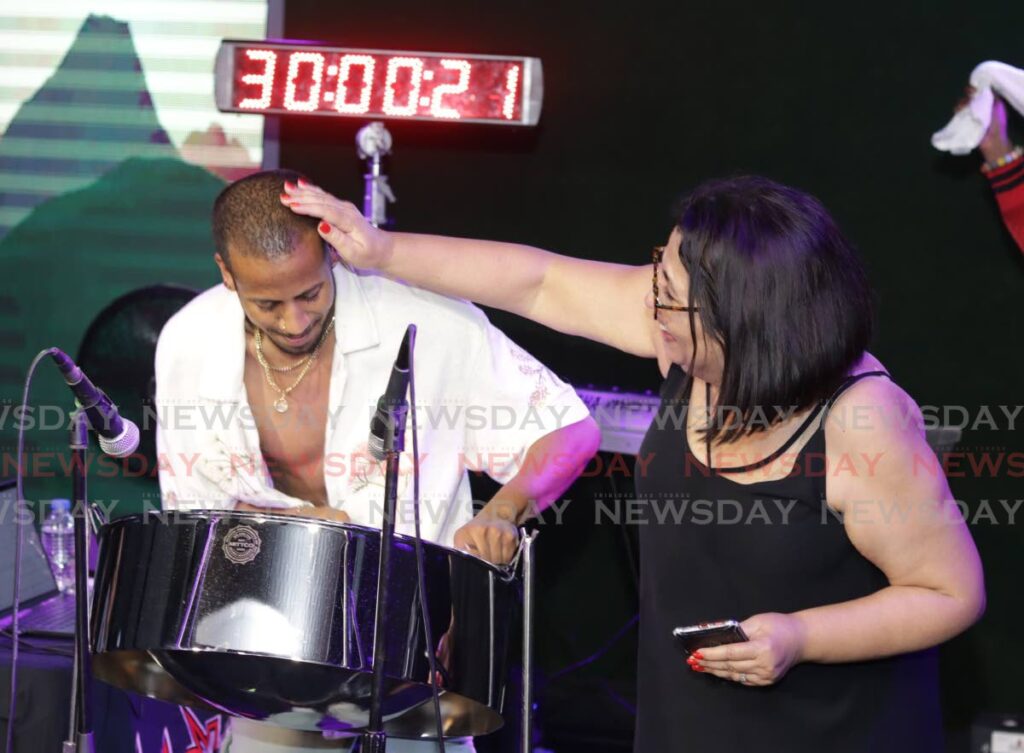 Joshua Regrello is congratulated by his mother Kamla Regrello after he crossed the 30-hour mark in his bid to enter the Guinness Book of World Records for the longest pan marathon on December 28 at Wack 90.1 FM radio station on Coffee Street, San Fernando. - Photo by Grevic Alvarado