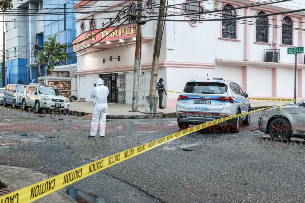 Crime Scene Unit investigators gather evidence outside the police station on Besson Street, Port of Spain, on December 28 following a gun attack. - Photo by Jeff K Mayers