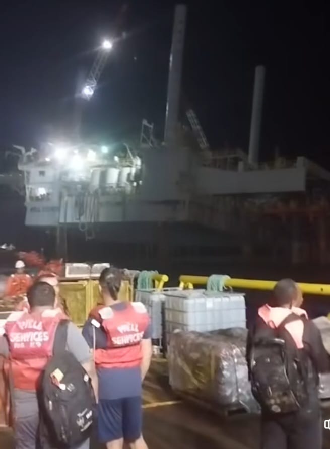 Well Services workers look on at the damaged rig on December 22. -