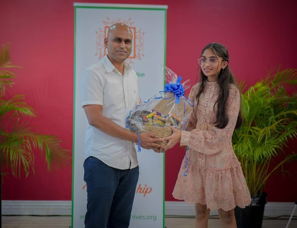 Glen Ramdhani, CEO of NOVO Farms presents a token to the first-place winner Samara Saroop. - 