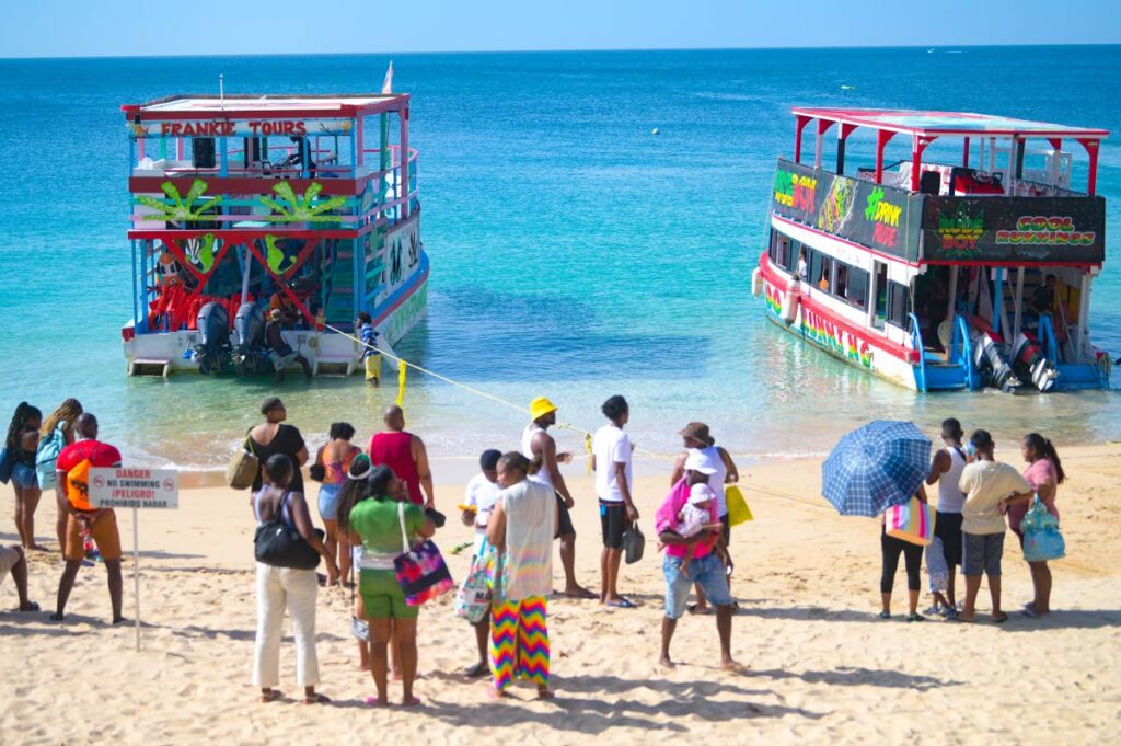 People wait to board glass-bottom boats at Store Bay on Christmas Day, ahead of tour of the Buccoo Reef. - Photo by Visual Styles