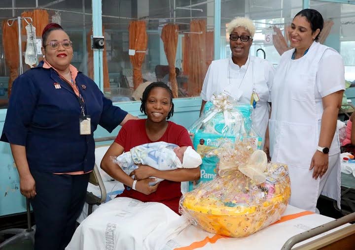 From left, Michelle Benjamin-Foster, patient care co-ordinator, embraces a smiling Adesha Luke as she cuddles her New Year’s joy. Also in the photo are Hazel Ann Mills, assistant head nurse and Cherry-Ann Hackshaw-Titte, RN/licensed midwife. - Photo courtesy South West Regional Health Authority