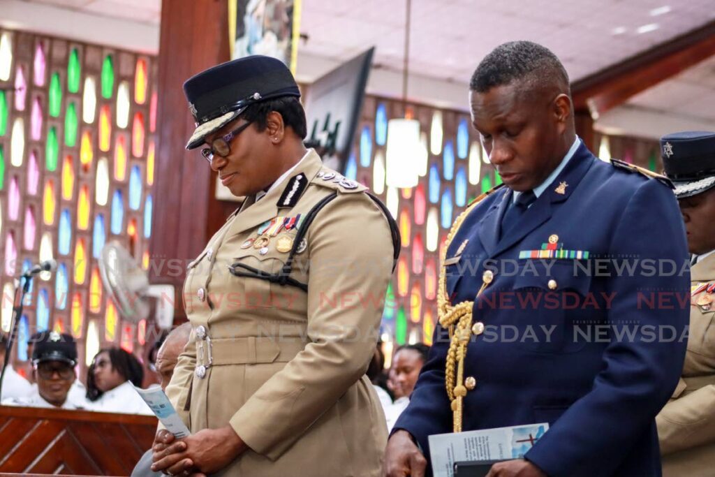 BOWED HEADS: Police Commissioner Erla Harewood-Christopher and Chief of Defence Staff Air Vice Marshall  bow their heads in prayer at the police service's annual interfaith service at St Paul's Anglican Church, San Fernando on January 5. - Photo by Grevic Alvarado