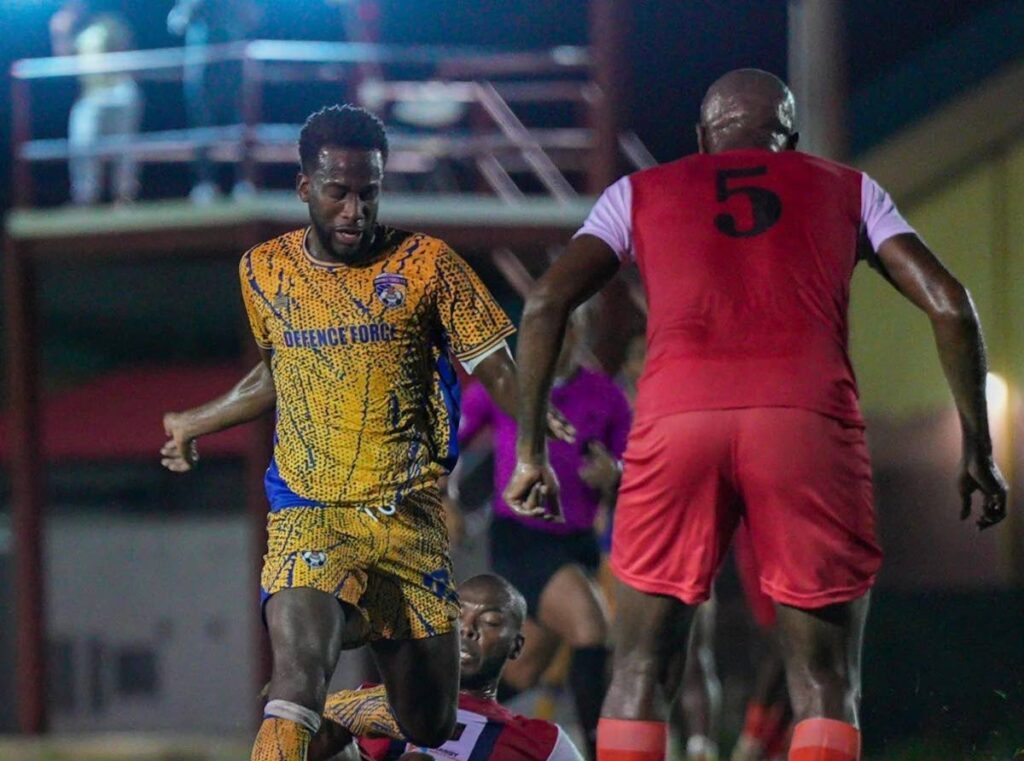 Defence Force attacker Kevin Molino is tackled from behind against Caledonia AIA at La Horquetta Recreation Ground on January 10. - Photo courtesy TTPFL