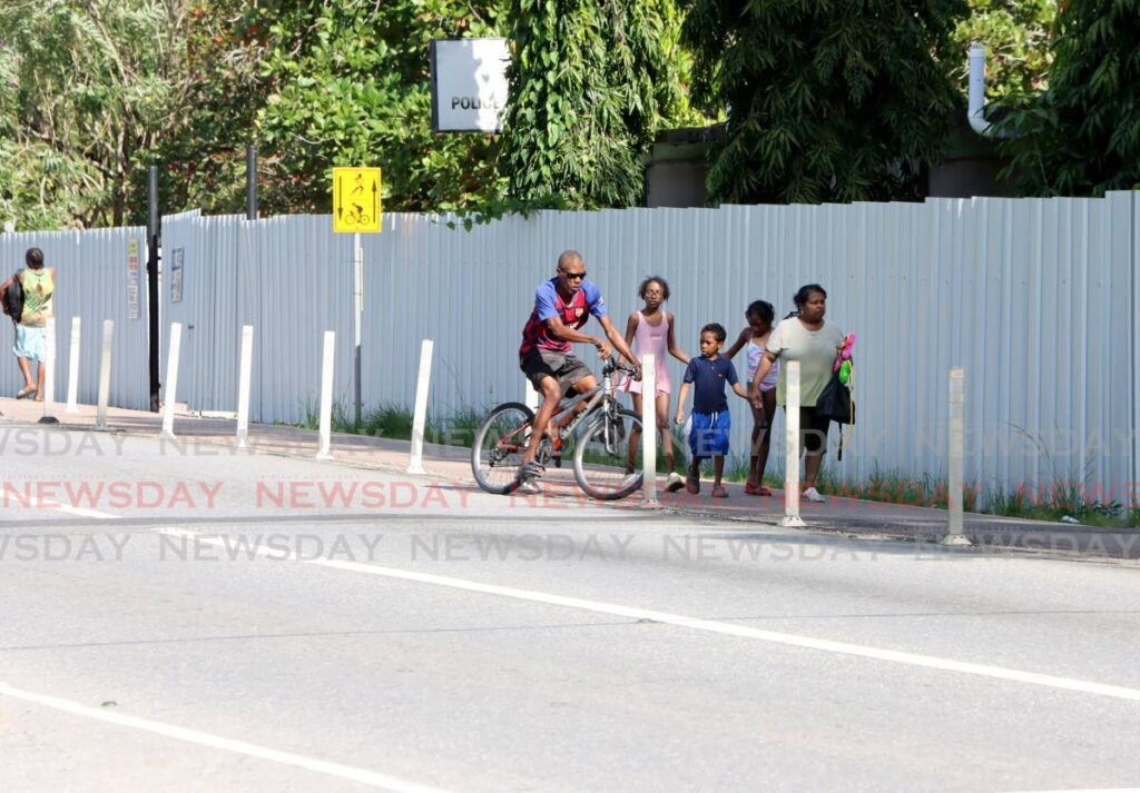 A man rides past a group of people walking along on the bicycle lane at the Chaguaramas Boardwalk on January 12. - Photo by Ayanna Kinsale