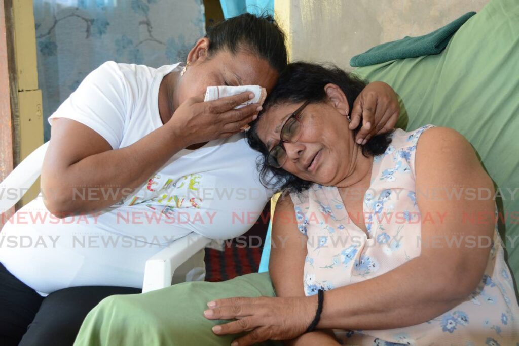 Sarah Ganpat, left, and her mother-in-law Sybil Ramcharan console each other at their Phoenix Park, Couva home on January 17. They mourned Damian Ramcharan, 43, who was crushed to death by a cement truck on January 16. - Photo by Innis Francis