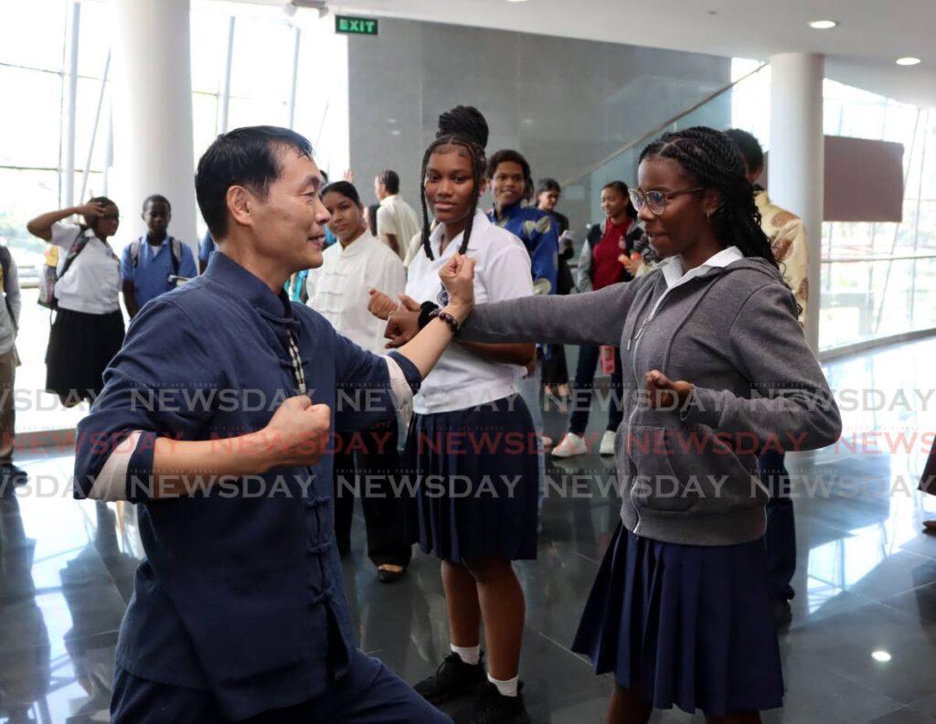 Jianrong Lu, left, a foreign lecturer, Centre for Language Learning, teaches tai chi to Woodbrook Secondary School students Sara Carimbocas, left, and Cianna Peters during the Navigating Growth and Opportunities Expo at NAPA, Port of Spain. January 17. - Ayanna Kinsale