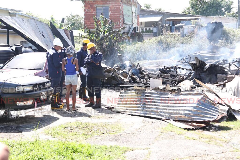 Fire officers speak with a relative of 79-year-old Hollister Hamilton at the scene of the house fire at Thompson Street Extension, Gasparillo that claimed Hamilton's life on January 23. - Photo by Lincoln Holder 