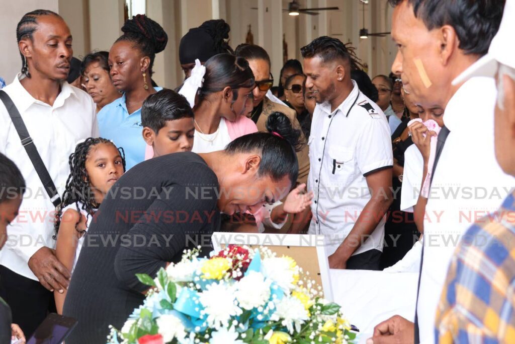  Ayesha Ali weeps over the sealed casket of her sister Sharida Ali during the funeral on Monday at the St Joseph RC Church. Ali was killed by a stray bullet in Beetham Gardens while police and soldiers were chasing bandits on January 18. - Photo by Faith Ayoung