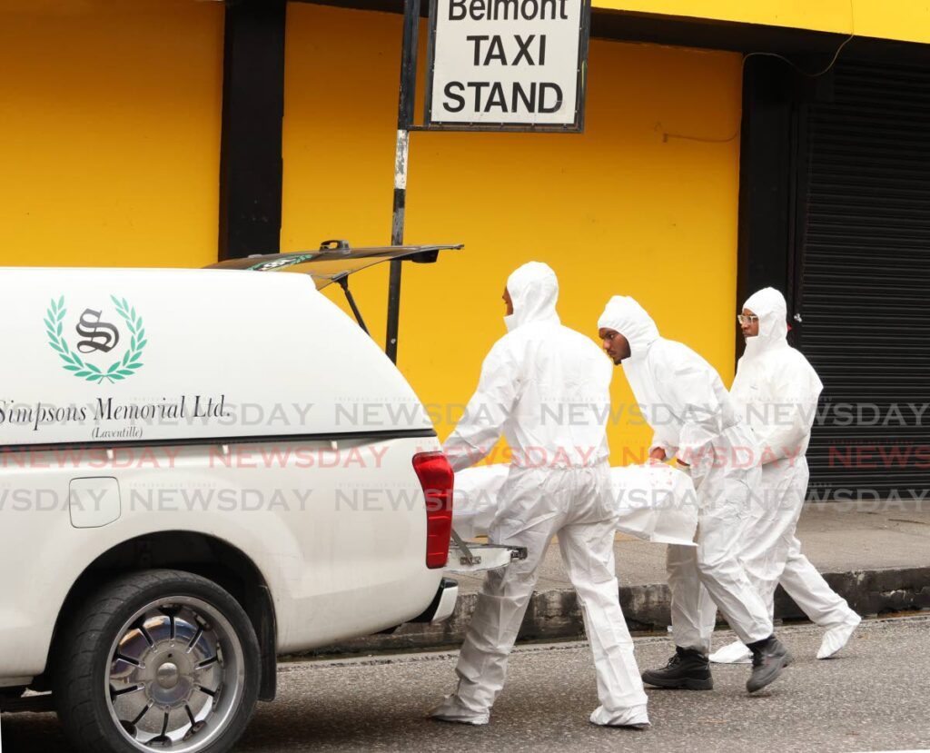 TAKEN AWAY: Crime scene police assist in removing the body of a would-be bandit who was shot dead on Charlotte Street in Port of Spain on January 27. - Photo by Faith Ayoung