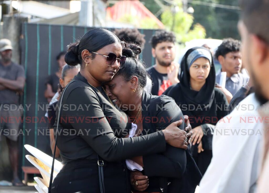 A TIME OF SORROW: A woman weeps at the funeral for murder victim Ameer Hosein on January 29 at the family's Frederick Settlement, Caroni home.  - Photo by Ayanna Kinsale