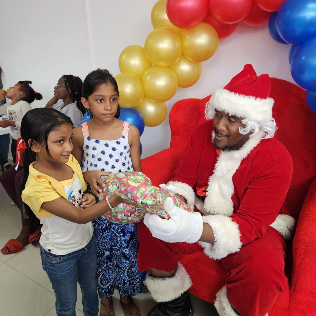 Santa Claus presents toys and clothing to children assembled at American Stores in St James during the Christmas Cheer event hosted by the Help Me Help You Foundation, in collaboration with Vybz Kartel, American Stores and the One Caribbean Unity Festival. - 