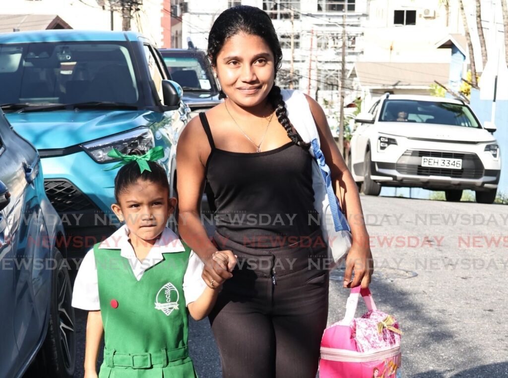 Sophie Dookie walks with her mother Radha Rampersad to St Gabriel's Girls RC School, San Fernando on January 6, the first day of the new school term. - Photo by Lincoln Holder