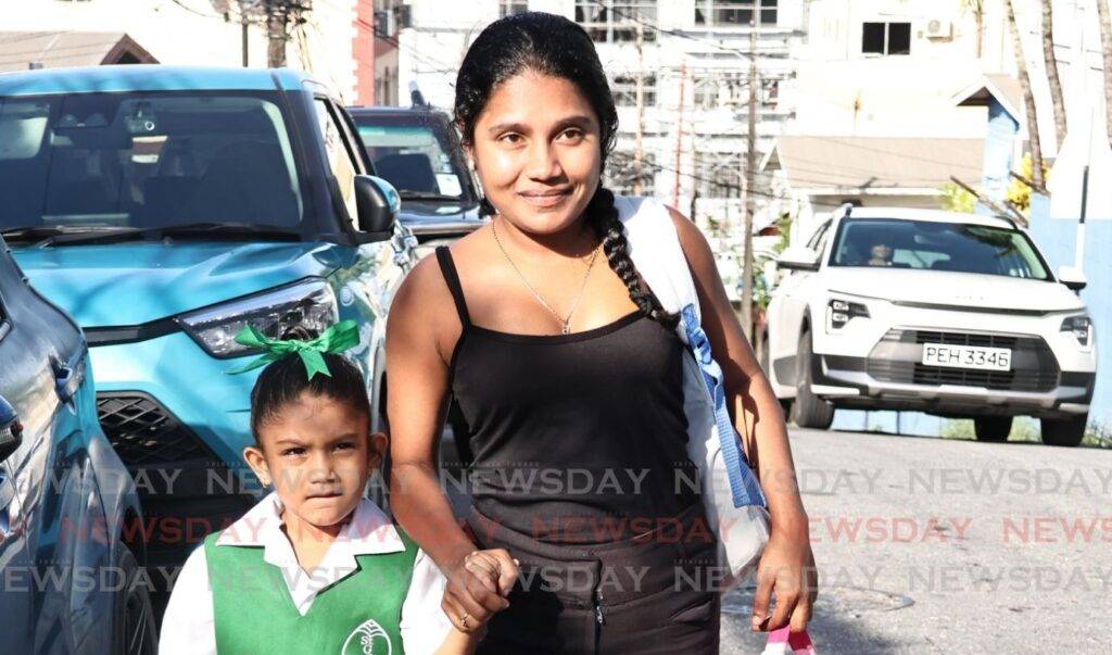 Sophie Dookie walks with her mother Radha Rampersad to St Gabriel's Girls RC School, San Fernando on January 6, the first day of the new school term. - Photo by Lincoln Holder