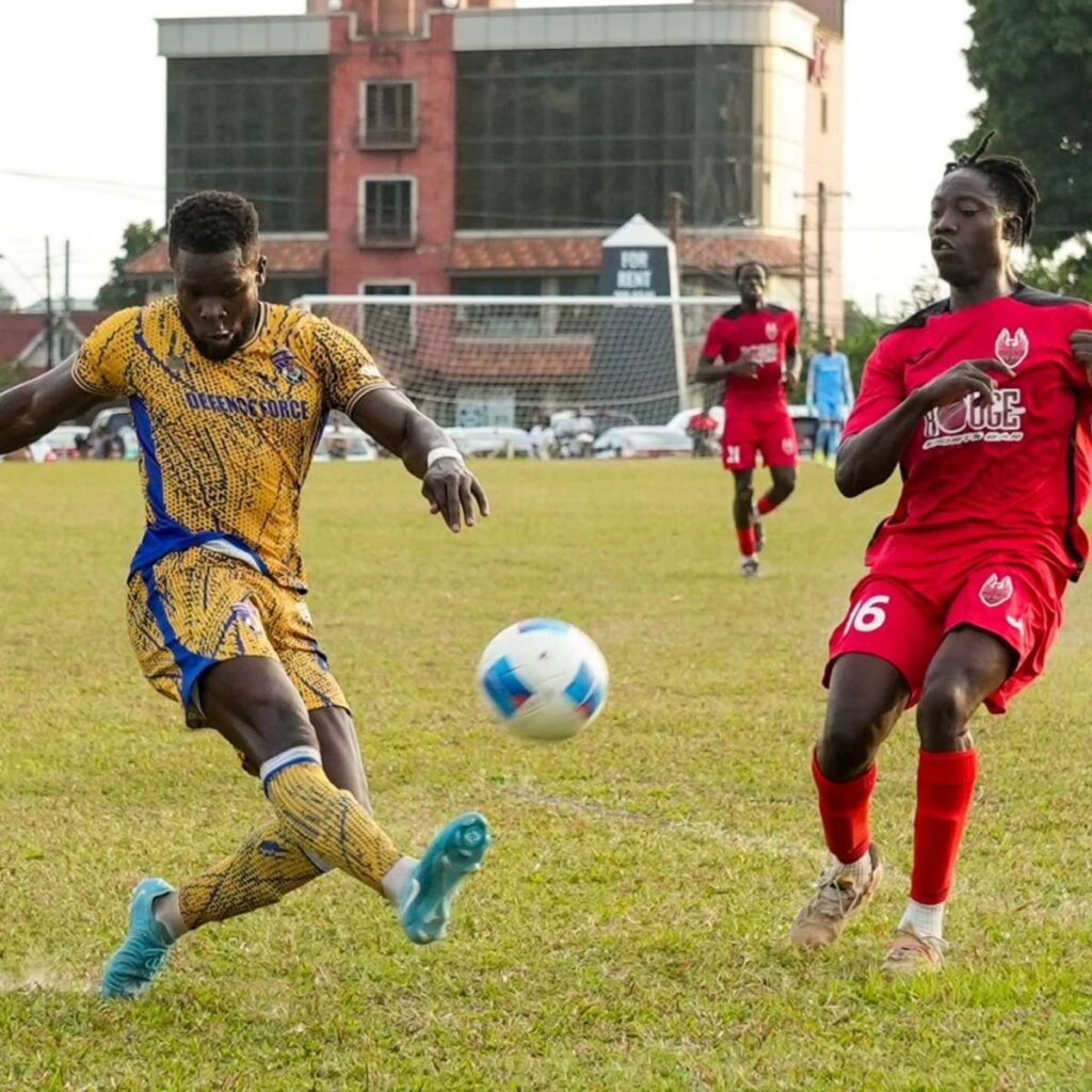 Defence Force's Isaiah Garcia, left, kicks the ball as 1976 FC Phoenix's Emanuel Cox tries to close him down in a TTPFL game on Sunday at Police Barracks, St James.   - Photo courtesy TTPFL