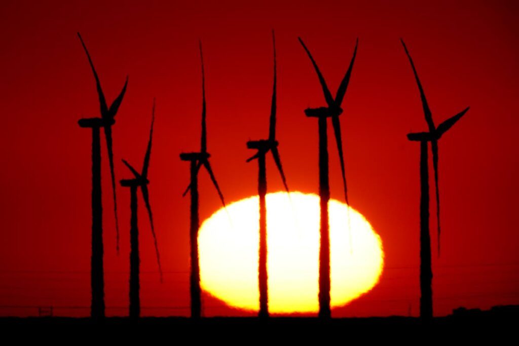 Wind turbines at the Buckeye Wind Energy are diffused by heat vapours as the are silhouetted against the rising sun, September, 2024, near Hays, Kan. (AP Photo/File) - 