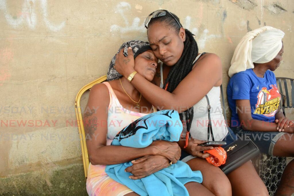 Betty King, left, mother of Kelita Jamal King, 16, holds on to her son's jacket while being consoled by Niketa Dayal at her home in Marabella on January 11. Kelita was killed in an accident on the night of January 10. - File photo by Innis Francis