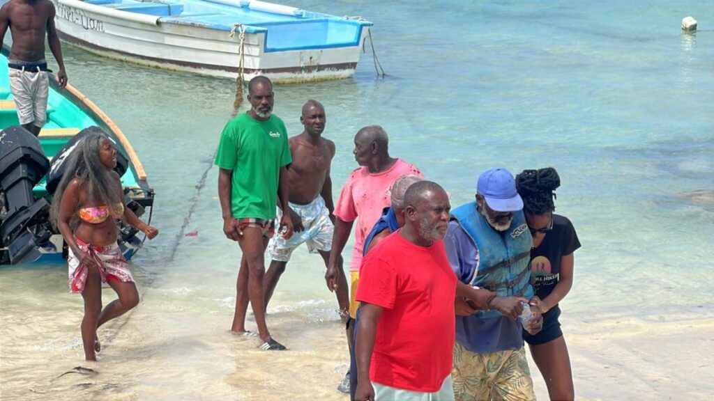 Tobago fisherman Albert James, centre, who was rescued at sea, is helped to shore by his daughter and an unidentified man at Pigeon Point on February 15. - Photo courtesy TEMA